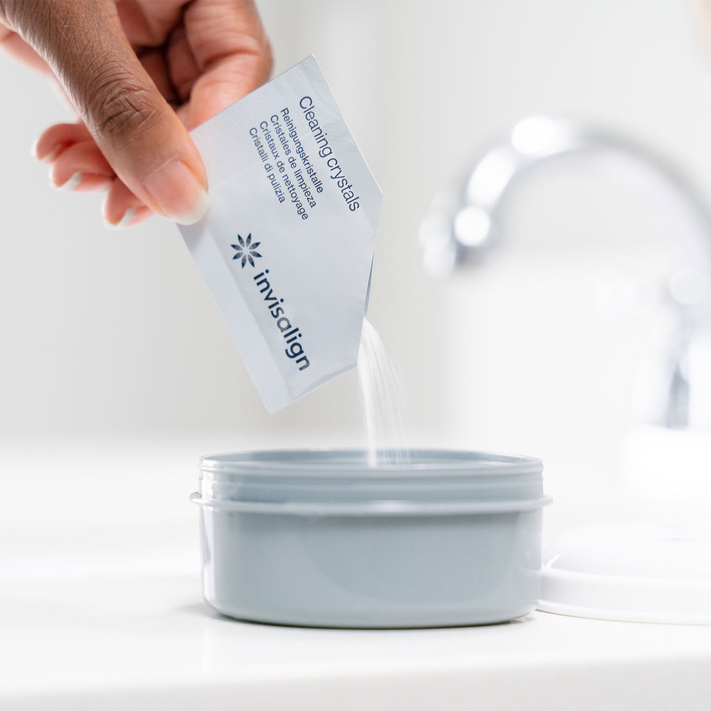 Hand pouring Invisalign cleaning crystals pack into tub